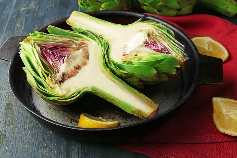 Rub half of the artichoke with a slice of lemon. Put artichokes in the baking dish.